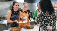 Meghan beams as she serves lunch at a women's homeless shelter after visiting a children's hospital with Harry on the first day of their whirlwind tour of Australia