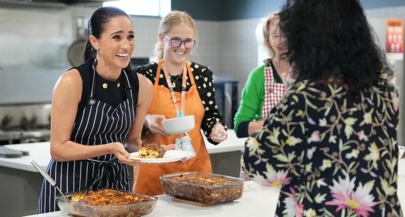 Meghan beams as she serves lunch at a women's homeless shelter after visiting a children's hospital with Harry on the first day of their whirlwind tour of Australia