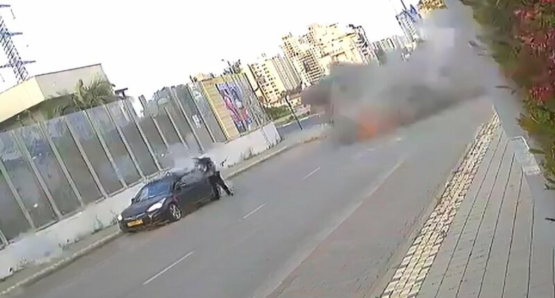 Moment Iran missile lands yards away from Israeli woman, who is knocked to the floor but miraculously manages to walk away