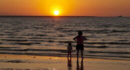 A woman and child watch the sun set at Mindil Beach in Darwin.
