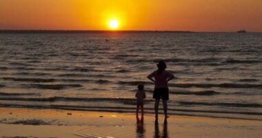 A woman and child watch the sun set at Mindil Beach in Darwin.
