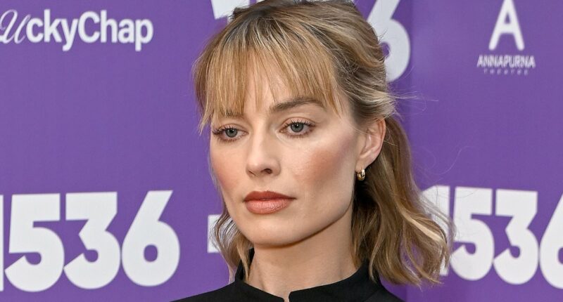 Margot Robbie flashes her toned midriff in a military-style jacket