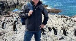 Fraser Allen (pictured with a penguin colony in Chile), 58, has spent the past one and a half years living on a cruise ship