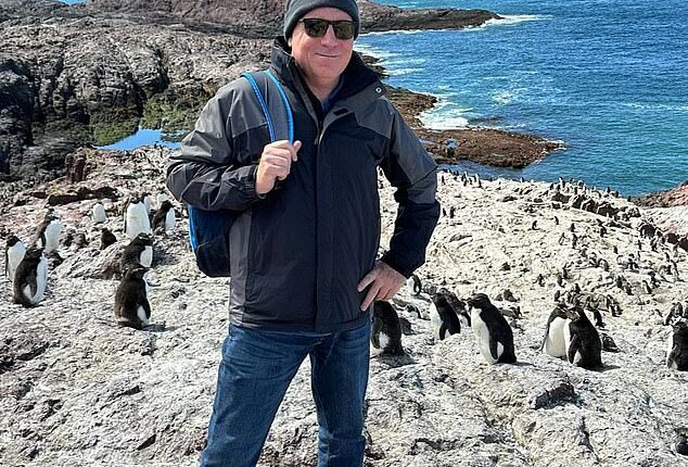 Fraser Allen (pictured with a penguin colony in Chile), 58, has spent the past one and a half years living on a cruise ship